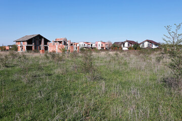 Houses under construction. Red brick. Gray house. Field.