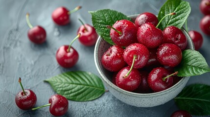   A bowl of cherries on the table is adorned with leaves and water droplets delicately resting atop each juicy fruit