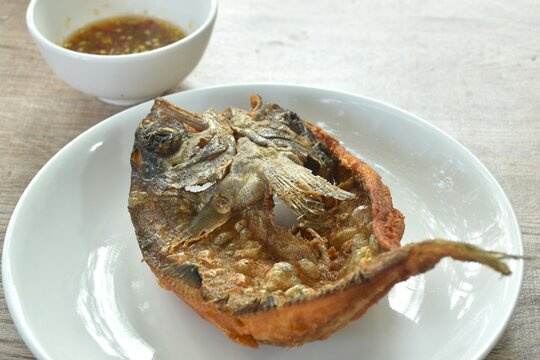 deep fried black-banded trevally fish on plate dipping spicy chili sauce  