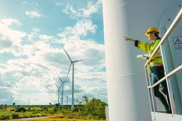 female engineer working outdoor with safety at wind turbines clean energy power station background, worker people with renewable energy technology for future concept. - 801166329