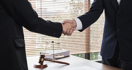 A lawyer and a businesswoman shake hands and reach an agreement on a cooperation contract document....
