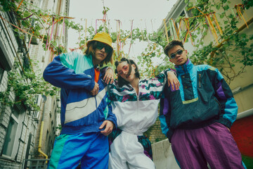 Three young people, friends wearing 90s inspired sportswear, colorful tracksuits and accessories,...
