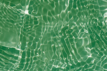 Green background with drops of water. Bluewater waves on the surface ripples blurred. Defocus...