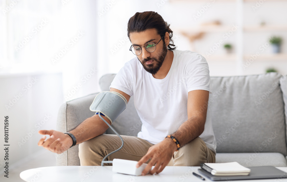 Wall mural man sitting checking blood pressure at home