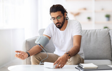 Man sitting checking blood pressure at home