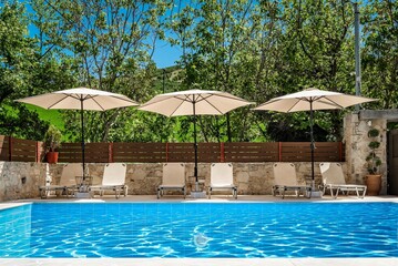 Swimming Pool Area with Sunbeds and Open Umbrellas, Perfect for Relaxation on a Bright Sunny Day. ...
