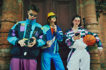 Creative urban trio. Three stylish young people, friend in 90s inspired sportswear posing against vintage architectural background. Concept of 90s, fashion, youth culture, old-style trends