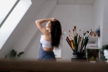 Young female artist paints a picture with oil on canvas in art studio