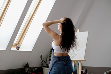 Young female artist paints a picture with oil on canvas in art studio