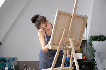 Young female artist paints a picture with oil on canvas in art studio