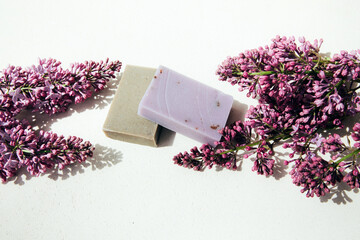 A bar of natural soap with lilac flowers on a concrete background. Cosmetics from natural ingredients, herb. Top view - obrazy, fototapety, plakaty