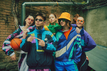 Youthful spirit of street fashion. Stylish young people, boys and girls wearing vintage inspired street clothes, tracksuits, posing outdoors. Concept of 90s, fashion, youth culture, old-style trends