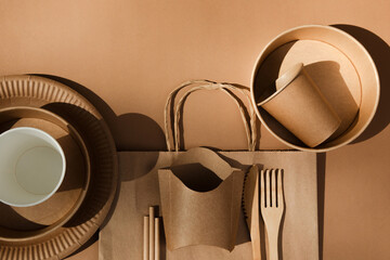 A set of paper utensils and wooden cutlery on a brown background. Eco friendly, zero waste concept....