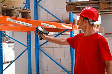 Worker in Distribution Warehouse With Handheld Barcode Reader Scanner Technology