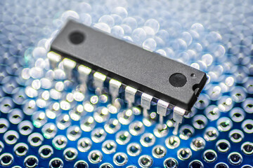 DIP package integrated circuit microchip on a blue printed circuit protoboard or breadboard.