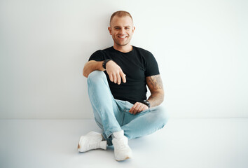 Young handsome man portrait sitting on floor in sun lights with copy space