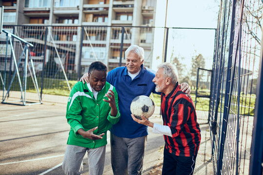 Senior friends playing soccer together in urban park