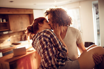 Romantic couple kissing in cozy home kitchen