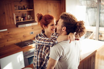 Romantic couple kissing in cozy home kitchen - obrazy, fototapety, plakaty