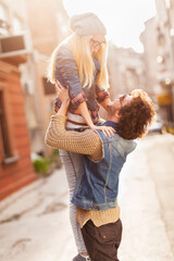 Happy young couple piggyback riding and laughing in urban setting