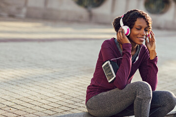 Active young woman resting and listening to music with headphones outdoors