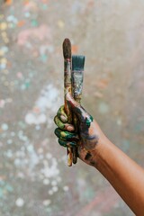 Hands holding paint brush, covered in paint