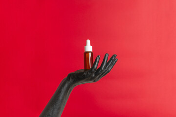 Black painted hand on her skin with cosmetic glass tube. Luxury product cosmetic advertising. Image for your design