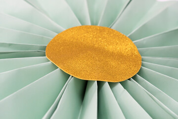 Folded green paper flower with gold glitter center. Crafts for decoration.