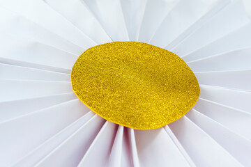 Folded white paper flower with gold glitter center. Crafts for decoration.