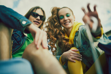 Stylish young man and woman wearing colorful clothes mixing with denim outfit, sunglasses spending relaxing time outdoor on sunny day. Concept of 90s, fashion, youth culture, old-style trends