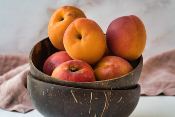 wo stacked coconut shell bowls filled with ripe apricots, emphasizing a rustic and organic presentation