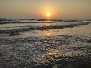 The image captures a serene beach scene at sunset.