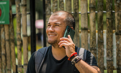retrato de hombre hispano latino llamando por teléfono celular al aire libre 