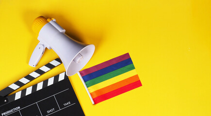 Clapper board and rainbow pride flag and megaphone on yellow background. - obrazy, fototapety, plakaty