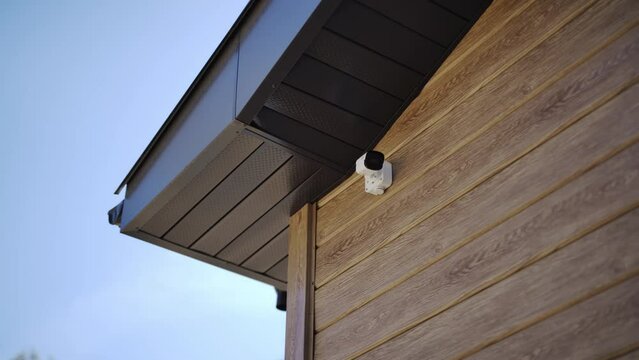 Modern wooden cottage with CCTV security camera system placed on wall under roof. Safety equipment protects owners from potential threats