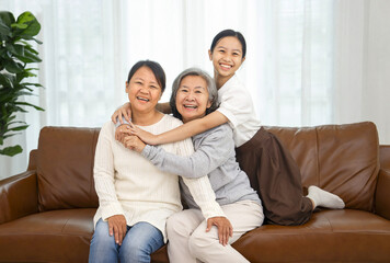 portrait happy family grandma and granddaughter sitting on sofa in the living room,smiling and...