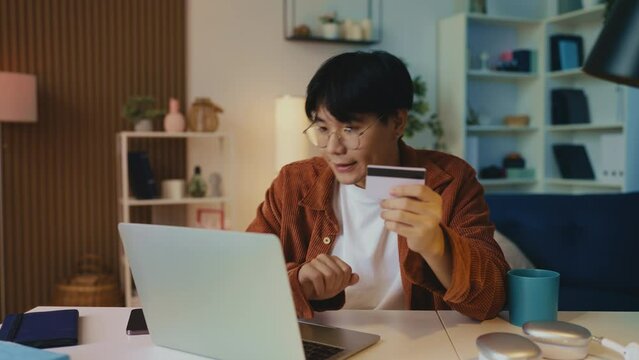 Sad Asian man having problems with online payment, entering credit card number