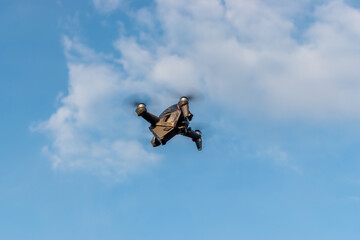 A new DJI FPV drone is flying during a sunny day on sky background.