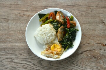 spicy stir fried Chinese kale with fish can in tomato sauce topping egg on rice 