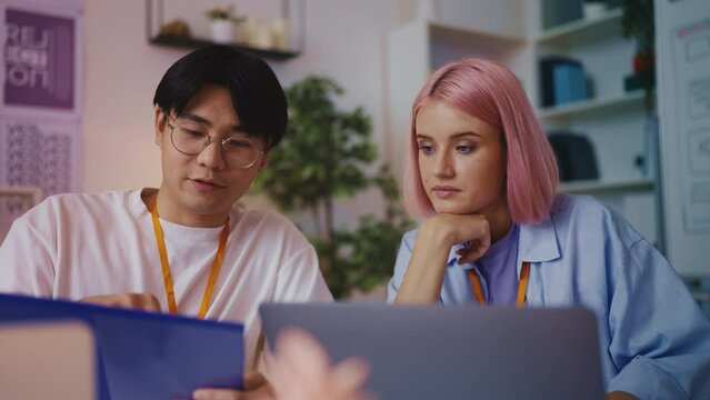Focused pink-haired web developer listening to colleague, discussing new project