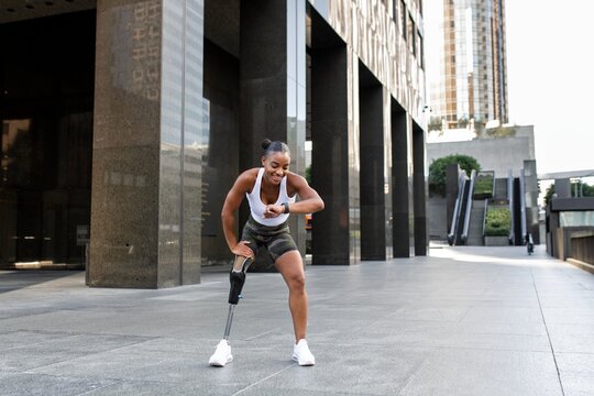 Woman with prosthetic leg looking at her smartwatch fitness tracker - Powered by Adobe