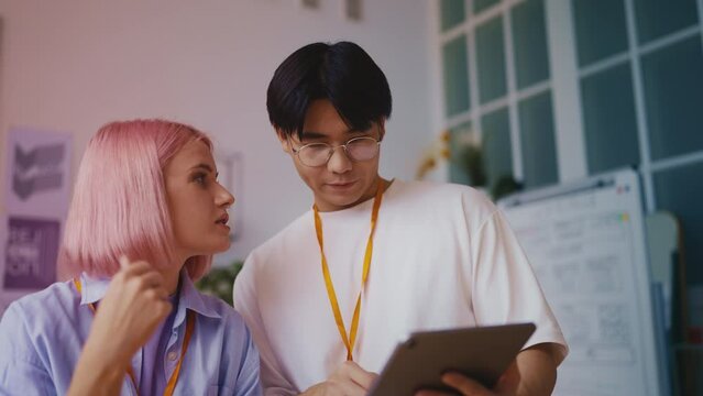 Young multiracial game developers discussing new work project on a tablet