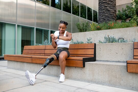 Woman with prosthetic leg looking at her smartwatch - Powered by Adobe