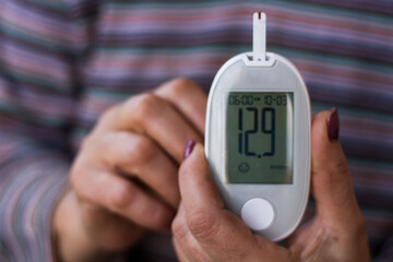 Hand holding a blood glucose meter measuring blood sugar. Extremely high blood sugar. Diabetes tipe...