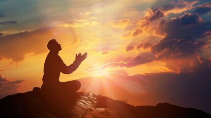 Silhouette of a person kneeling with his arms open and looking at the sky at sunset