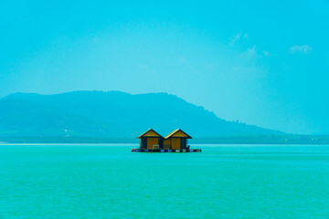 Small floating houses between the horizon line that separates the sea from the sky and set against...