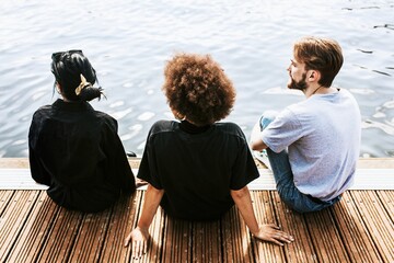 Three diverse friends sitting by the river bank