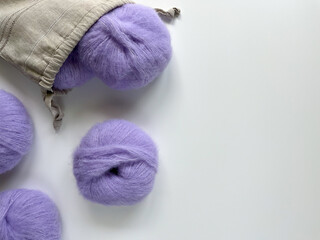 Violet woolen skeins of yarn for knitting fell out of the handmade linen bag. Supplies for...