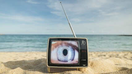 televisions with beautiful female eye on the screen next to the sea - 801250126