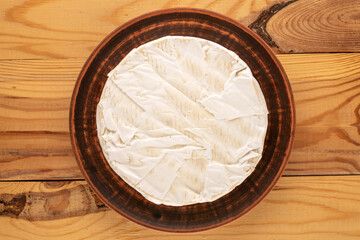 Brie cheese on a clay plate  on a wooden table, macro, top view.